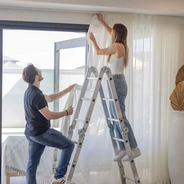 Two people managing sheer curtain installation