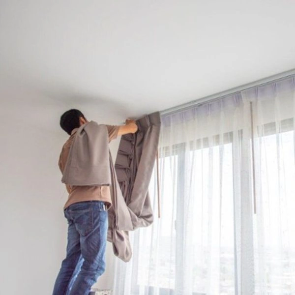 Worker fixing track during curtain installation