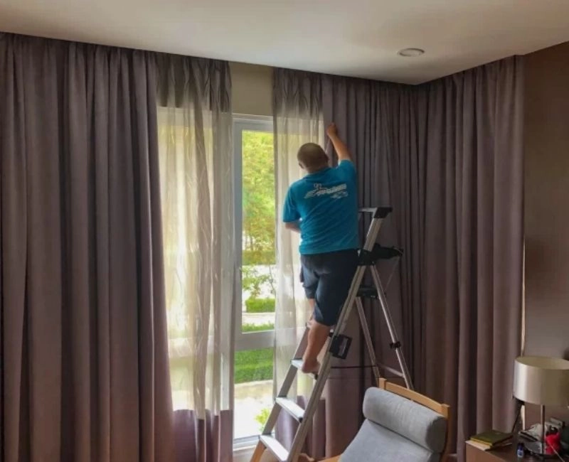 Worker on ladder doing curtain installation