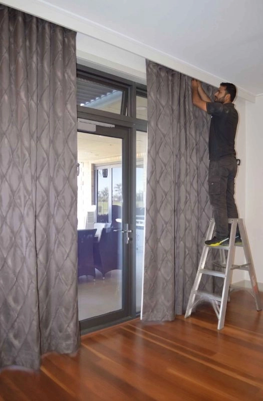 Worker fixing heavy brown curtain installation