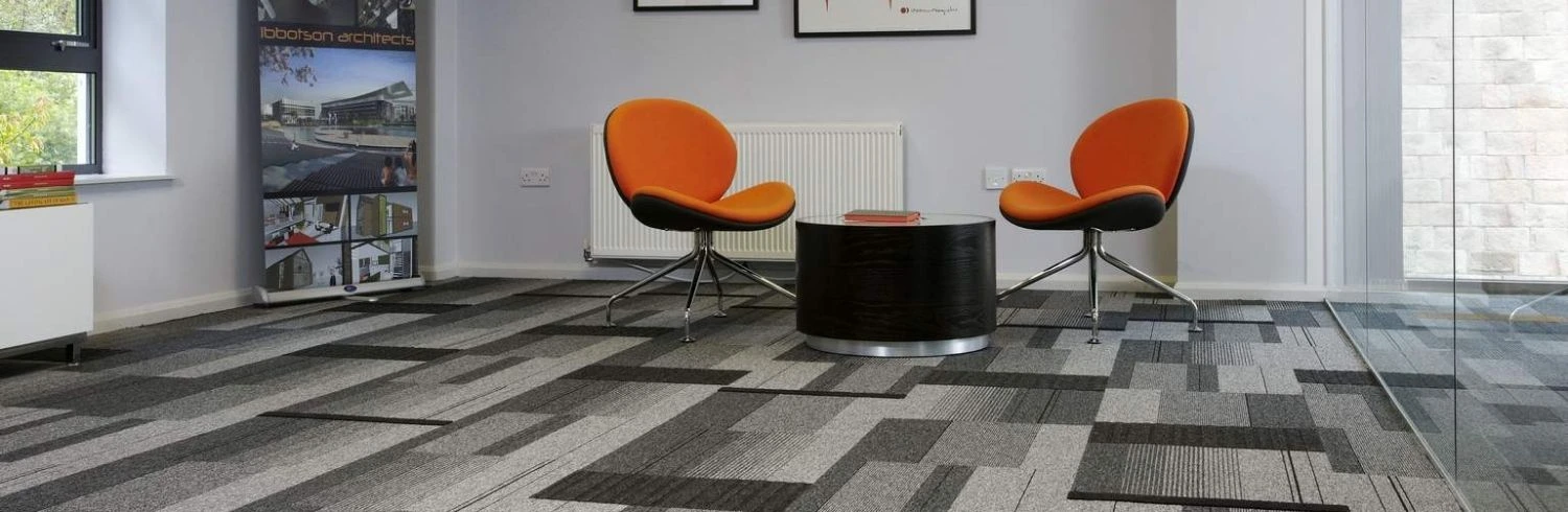 Grey patterned carpet tiles with orange chairs
